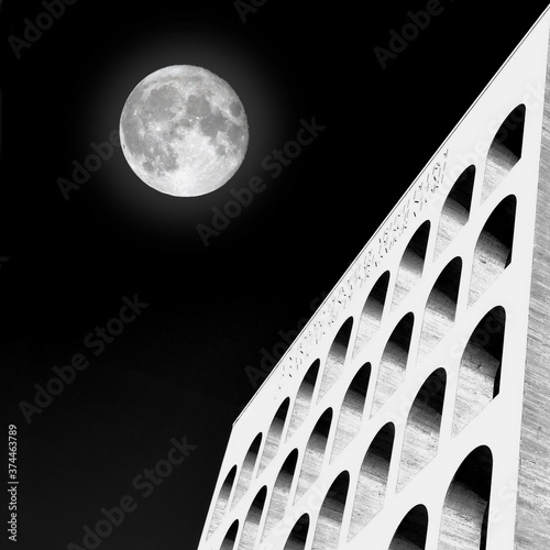Surreal image of the Palazzo della Civiltà del Lavoro Eur Rome with full moon. Photo black and white.