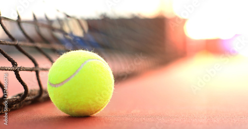 Bright greenish yellow tennis ball on clay court. © ty