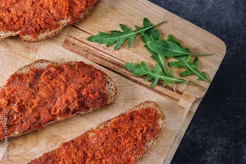 Fototapeta Naklejka Na Ścianę i Meble -  Typical mallorcan food made of bread slices with meat spread “sobrasada” on a wooden cutting board. Traditional gastronomy of Majorca.