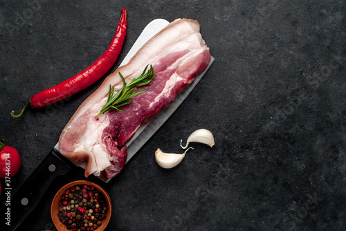 raw pork belly with spices over meat knife on stone background with copy space for your text