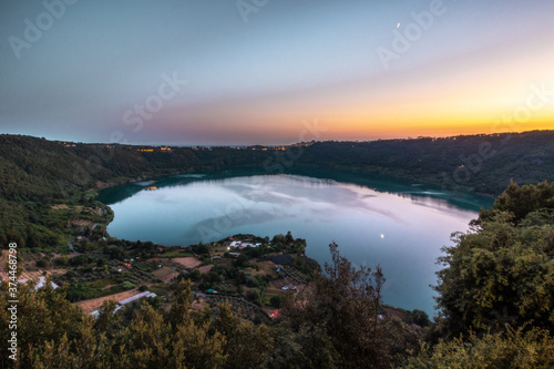 sunset over the lake in Nemi, Italy. reflection of the moon in the water.