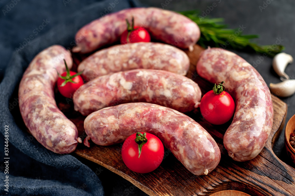 raw grilled sausages with spices on a cutting board on a stone background