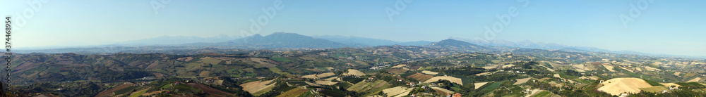 Italian rural landscape Marche countryside with plowed fields ready for sowing, clear sky without clouds, Mediterranean vegetation, Apennine mountains in the background. 