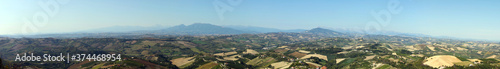 Italian rural landscape Marche countryside with plowed fields ready for sowing, clear sky without clouds, Mediterranean vegetation, Apennine mountains in the background. 