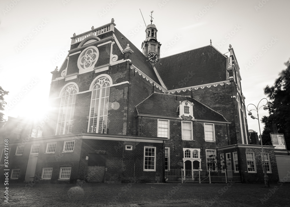 Fototapeta premium Amsterdam, Holland, the Netherlands - July 6 2020: capture of the typical Amsterdam scenery in black and white with canal, canalo house, clouds and the iconic buildings of the city