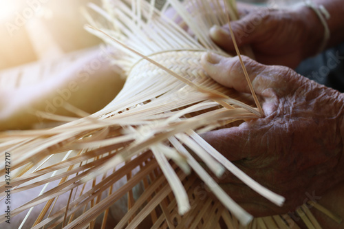 blur finger Old man's hands are weaving bamboo, Isan culture, Thailand. Independent career concept of old age. Thai handmade product. (selective focus) photo