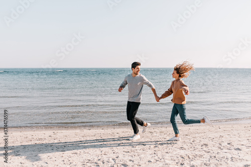 Cheerful young woman spending weekend at ocean resort with husband. Outdoor photo of cute couple expressing love on sea background.