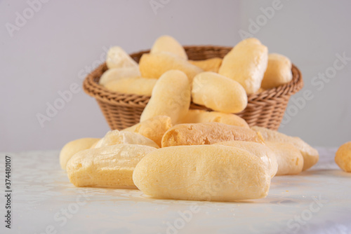 Traditional Brazilian starch biscuit called biscoito de polvilho in a basket on a table covered with white tablecloth, selective focus. photo