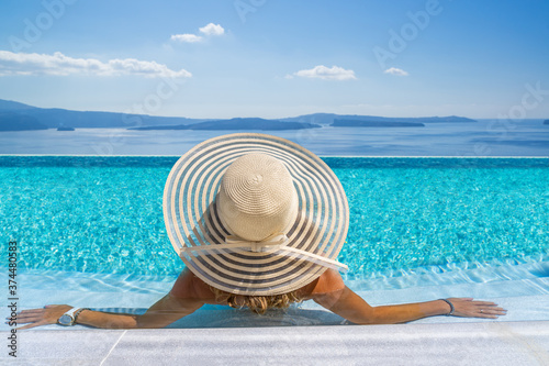 Fototapeta Naklejka Na Ścianę i Meble -  Woman at the swimming pool on the island of Santorini in Greece with view on the calde