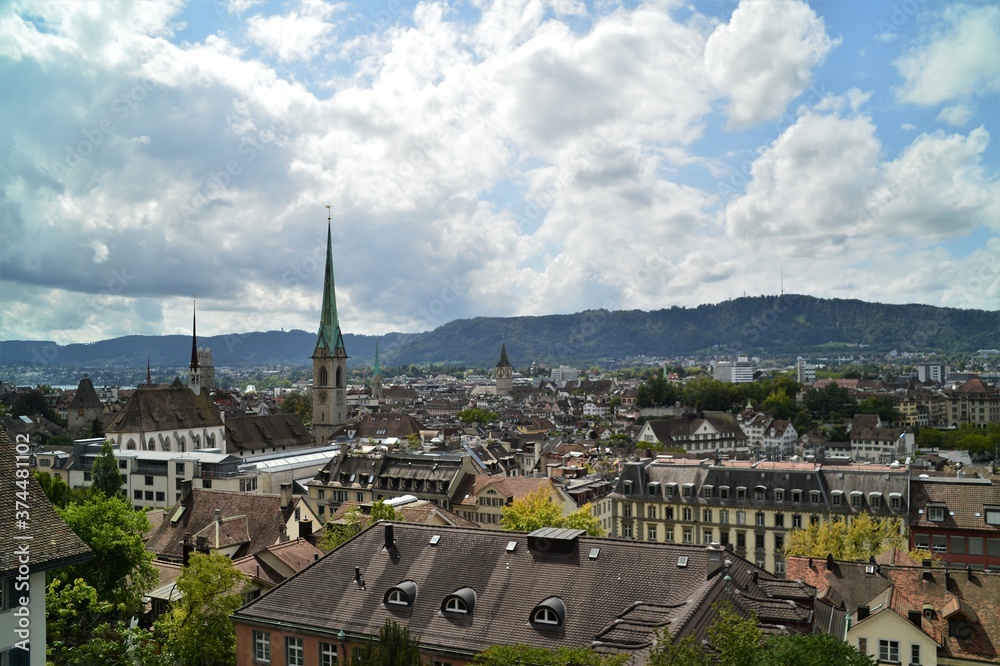 House roofs of Zurich with Predigerkirche and Grossmünster on a summer day with white clouds