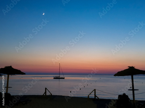beautiful sunset at the beach with boat and moon