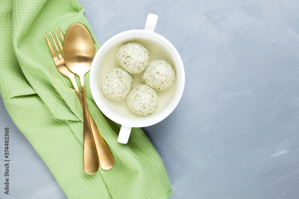 Meatballs with spinach in bone broth. Prepared from homemade minced chicken or turkey. A healthy dietary product with collagen. Gray background, copy space