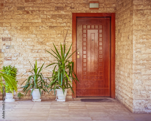 contemporary stonewall house with wooden entrance door and flowerplants, Athens Greece photo