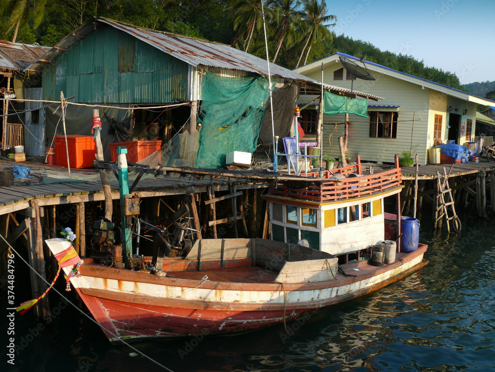 The fishing village houses a wooden bridge and a fishing boat.