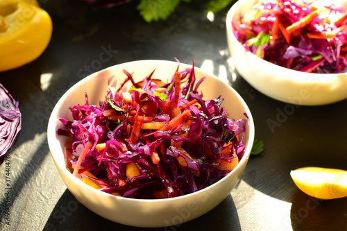 Red cabbage salad with bell peppers and carrots. Dark background. Healthy bright food.