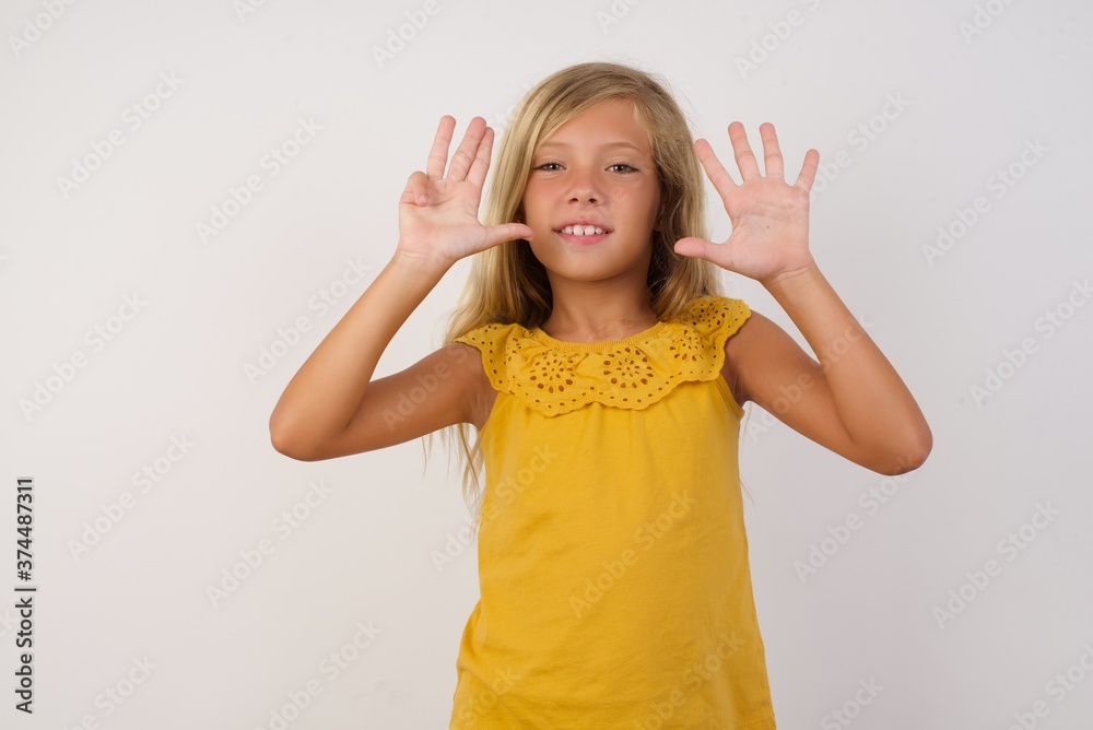 Young blonde kid girl wearing yellow dress over white background showing and pointing up with fingers number nine while smiling confident and happy.