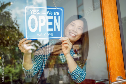Obraz na płótnie Closeup hand of Asian young woman setting open sign at the shop glasses for welcome the customer in to the coffee shop, small business owner and startup, installing open and close label concept w salonie