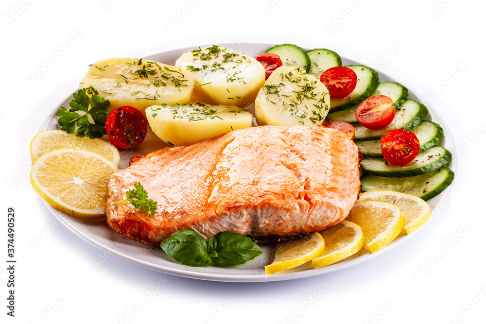 Fried salmon steak with potatoes and vegetables on white background Fried salmon steak with potatoes and vegetables on white background