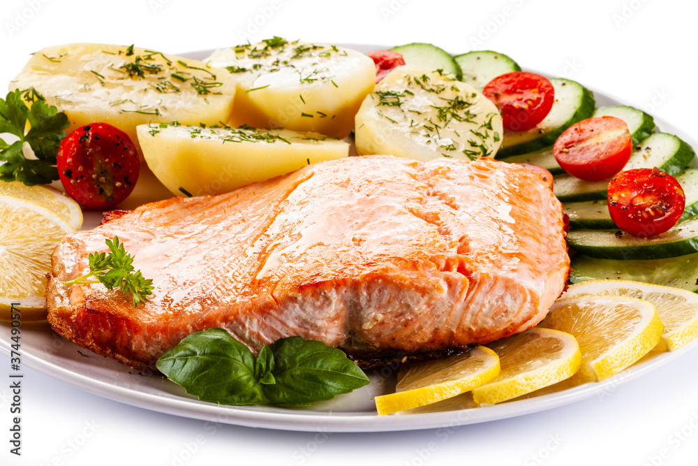 Fried salmon steak with potatoes and vegetables on white background Fried salmon steak with potatoes and vegetables on white background