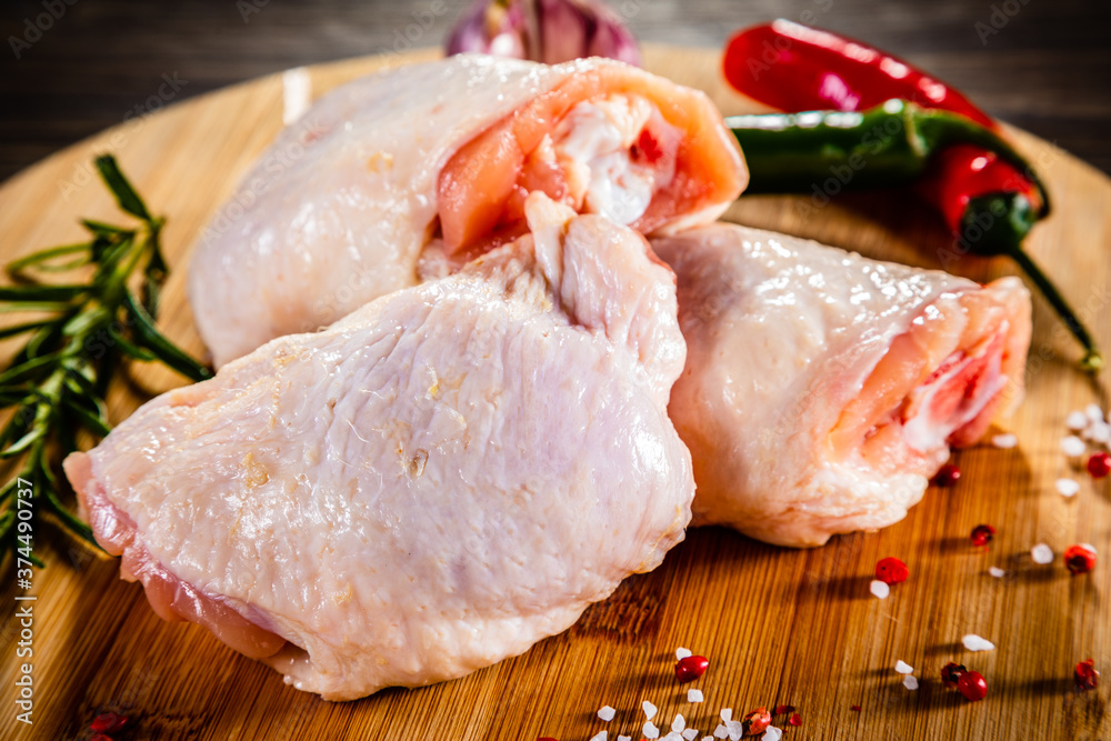 Raw chicken thighs on cutting board on wooden table
Raw chicken thighs on cutting board on wooden table