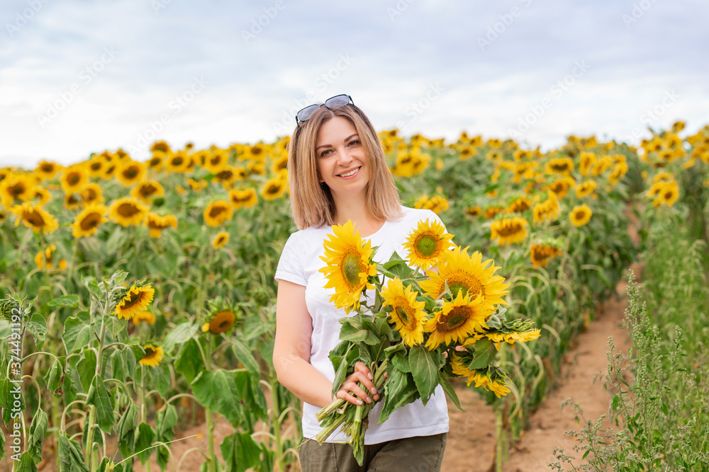 Sunflower field. A beautiful girl in a white T-shirt among many blooming sunflowers. Sunflower field. A beautiful girl in a white T-shirt among many blooming sunflowers.