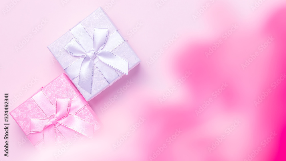 Beauty. Festive greeting banner poster for advertising or postcard, gift wrapping, silver box with a bow of ribbons in the haze for the holiday on a pink background with raspberry smoke top view Beauty. Festive greeting banner poster for advertising or postcard, gift wrapping, silver box with a bow of ribbons in the haze for the holiday on a pink background with raspberry smoke top view