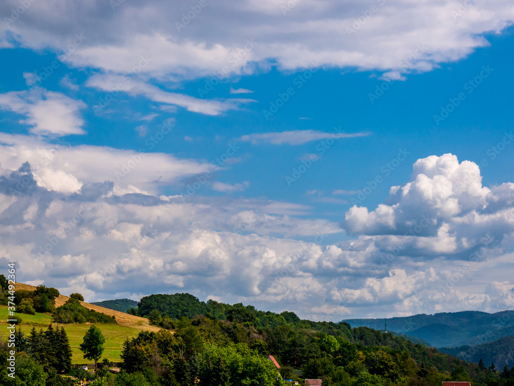 Cumulus congestus or towering cumulus - forming in the blue sky over hilly landscape