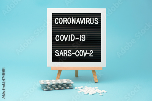 Writing board with medicine blister packs and scattered pills. Treatments for COVID-19. isolated on blue background. Horizontal shot. photo