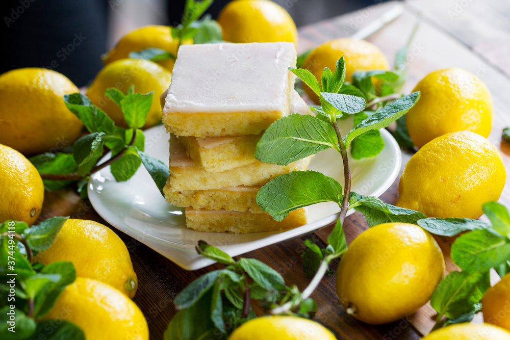 Sliced shortcake, many lemons and mint on wooden table Sliced shortcake, many lemons and mint on wooden table