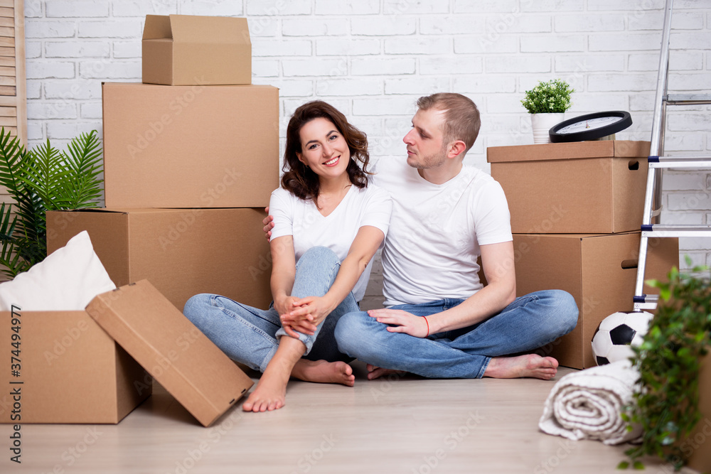 moving day concept - happy couple resting after moving in new house or flat moving day concept - happy couple resting after moving in new house or flat
