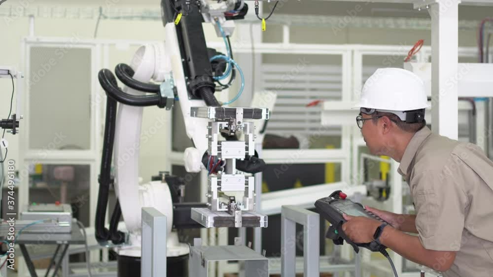 Engineer setting up automatic robot arms in smart factory, automotive industry, industrial concept. Engineer setting up automatic robot arms in smart factory, automotive industry, industrial concept.