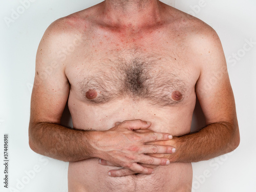 Young muscular fitness man holding his stomach suffering strong abdominal pain. Isolated on neutral background. In stomachache  digestive problems and health care issues.