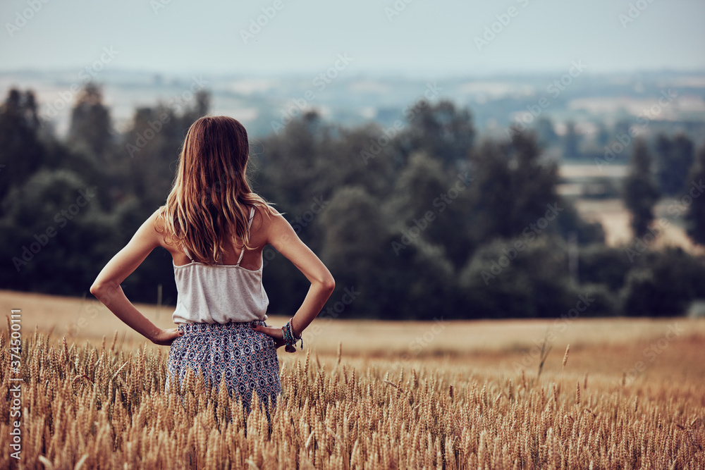 Young woman enjoying in a wheat field. - obrazy, fototapety, plakaty 