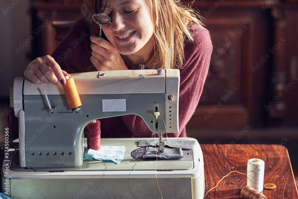 Woman tailor using retro sewing machine at home, hobby concept.