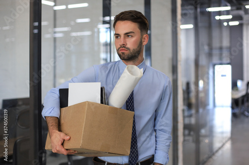 Sad dismissed worker is taking his office supplies with him from office.