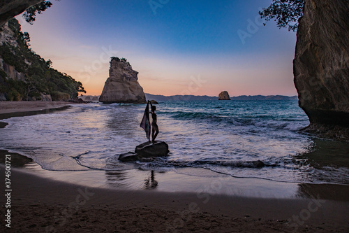 silhouette of a woman standing on a rock on the beach