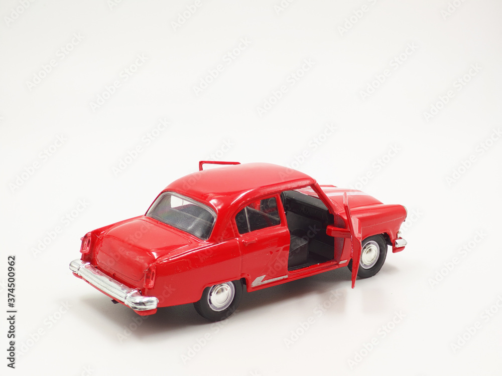 Vintage toy car red, with open doors, on a white background, view from behind.