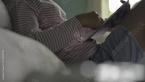 Wallpaper Mural Relaxing woman using digital tablet with social media apps and online texting in bedroom. Female teenager in casual dress reading an e-book on the bed. Computer device for modern life. Torontodigital.ca