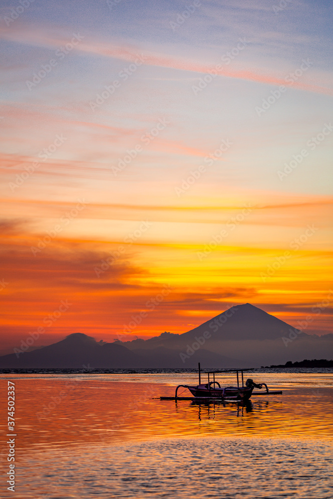 Traditional boat and volcano silhouette at sunset