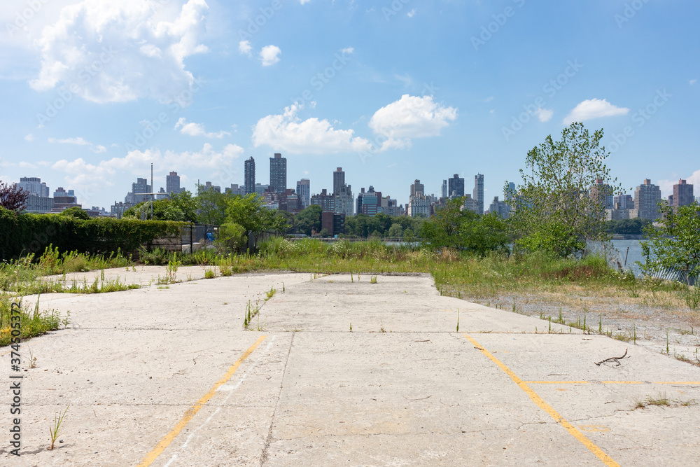 Vacant Land on the Riverfront of Astoria Queens New York with Overgrown Plants and a view of the Roosevelt Island and Manhattan Skylines
