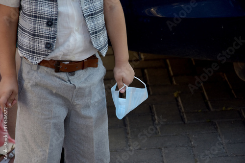 The child holds a protective medical mask in his hands.