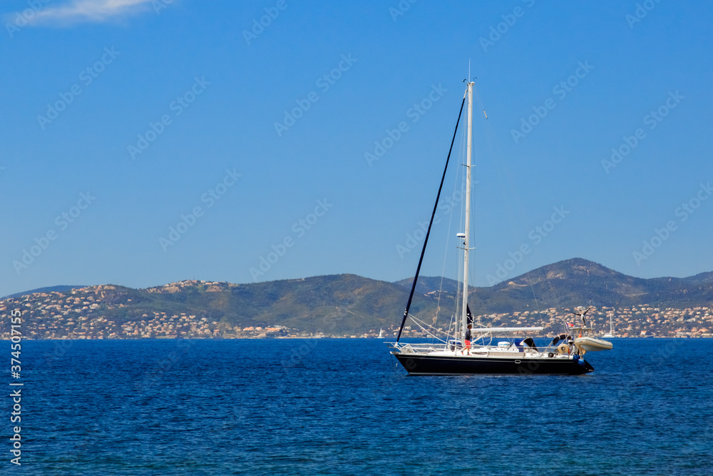one sailboat anchored off the coast with one man onboard