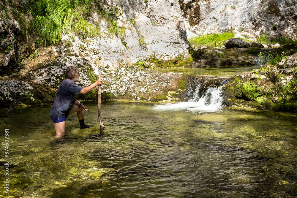 Adult hiker with a backpack on an adventurous hike through the canyon of the river Gačnik, Soca valley, Slovenia, Europe Adult hiker with a backpack on an adventurous hike through the canyon of the river Gačnik, Soca valley, Slovenia, Europe