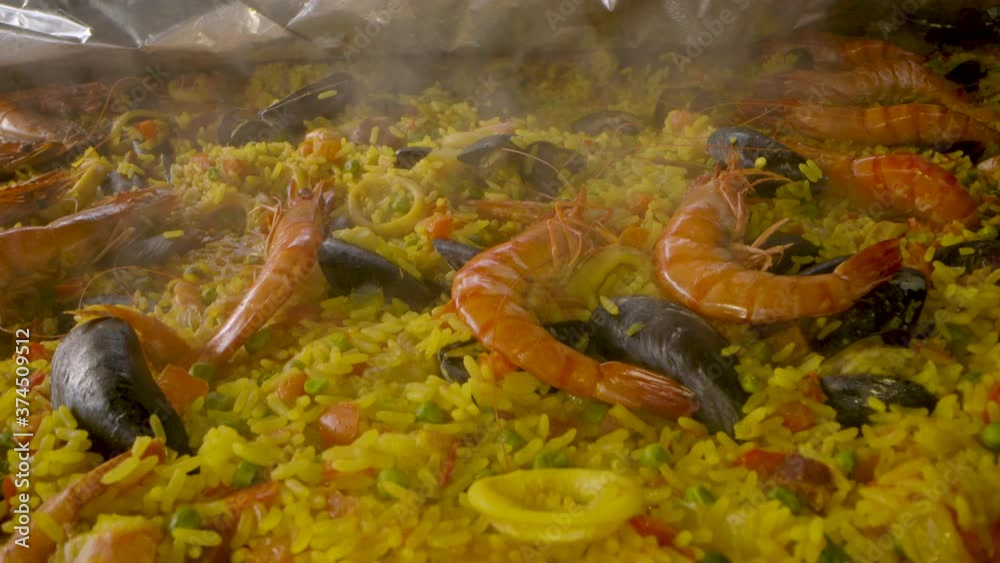 close up shot over a paella dish with prawns and tiger shrimp in a big pan. Sliding over the chicken legs and calamari on the saffron rice. close up shot over a paella dish with prawns and tiger shrimp in a big pan. Sliding over the chicken legs and calamari on the saffron rice.
