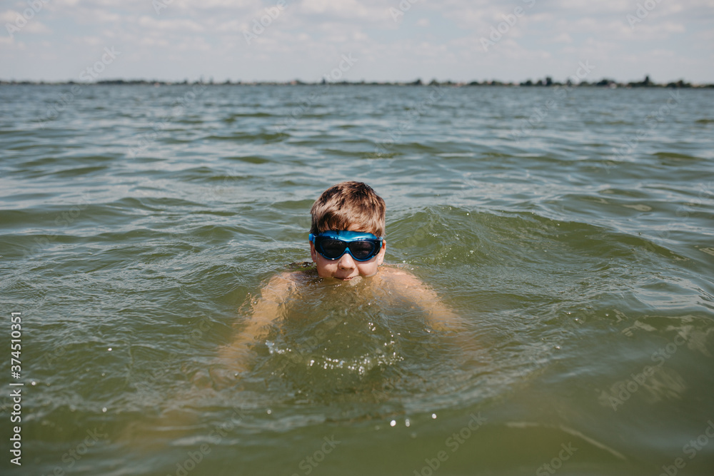 Teenager boy wearing goggles swimming in a lake Teenager boy wearing goggles swimming in a lake