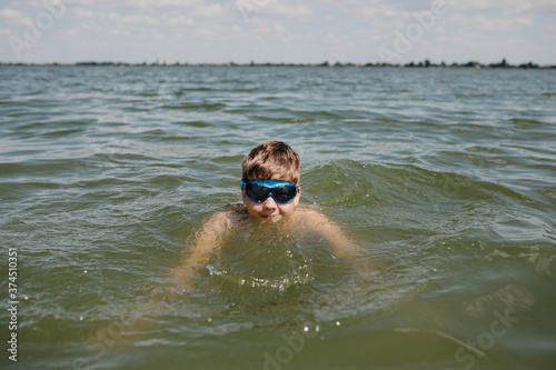 Teenager boy wearing goggles swimming in a lake