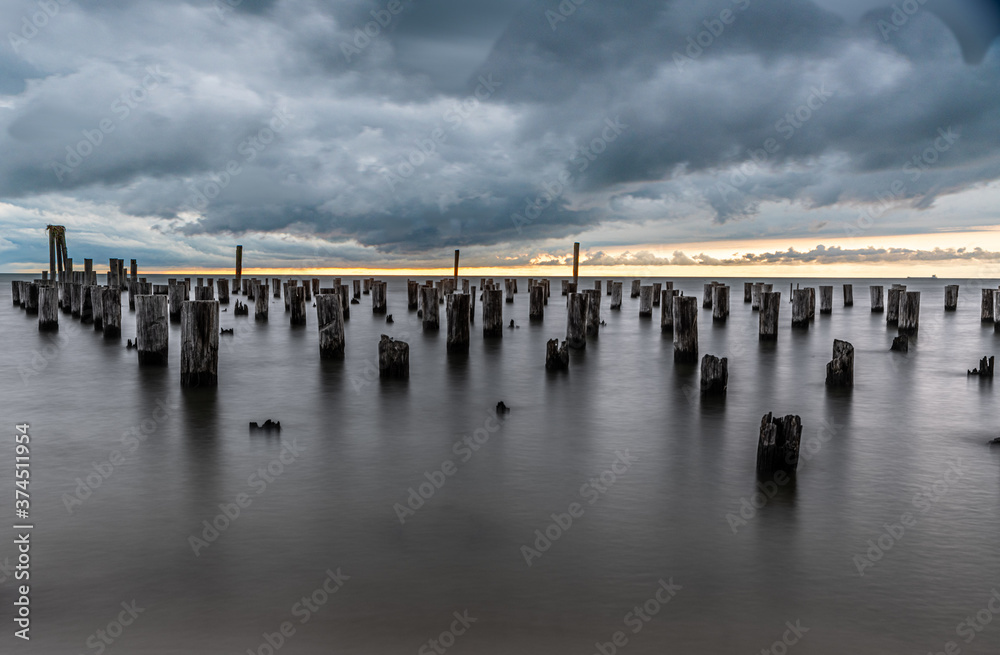 Pylons and coastline along the Eastern Shore of Virginia at sunset with a storm brewing in the background