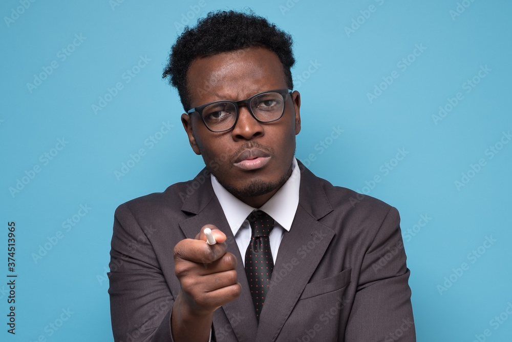 African man pointing finger, indicating direction to camera and looking annoyed