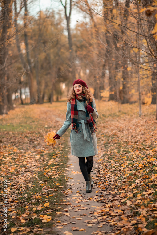 Girl on fabulous background of park with orange autumn leaves in hands walking on road. Pretty stylish smiling woman Girl on fabulous background of park with orange autumn leaves in hands walking on road. Pretty stylish smiling woman