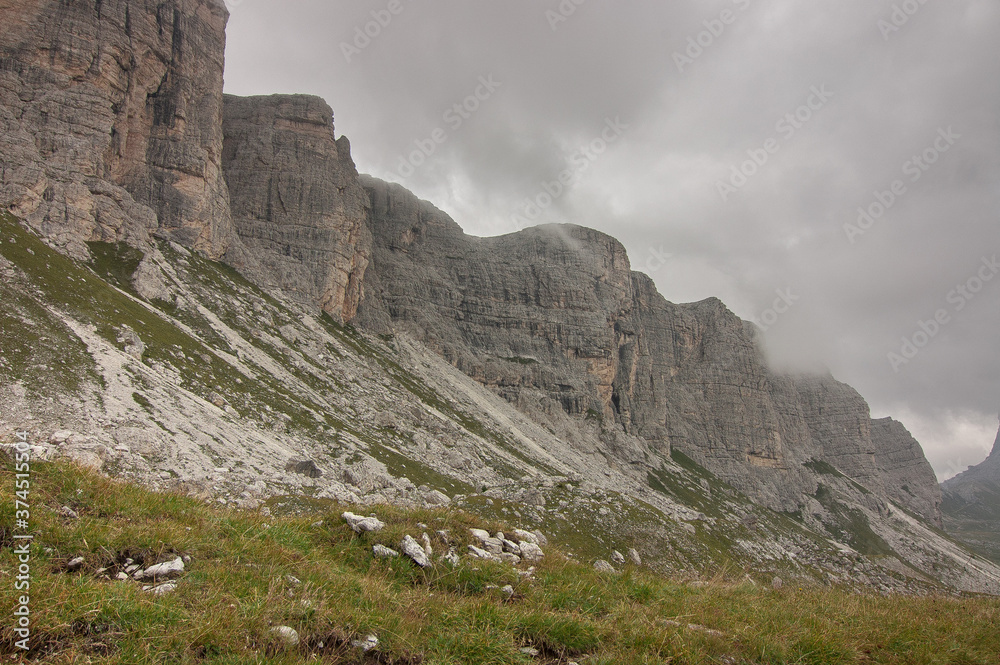 On route to Rifugio Citta di Fiume from Passo Giau over grassy, wild and rocky terrain on stage six of the classic Alta Via 1 trek, Dolomites, Belluno province, South Tyrol, Italy.